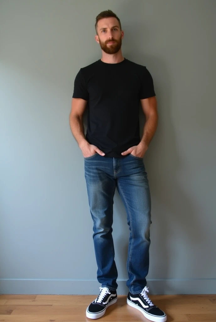 A man stands confidently against a minimalist gray wall, showcasing a casual yet stylish look. He wears a fitted dark black t-shirt that emphasizes his physique and is paired with classic blue denim jeans, featuring a subtle fade and a comfortable fit. His...