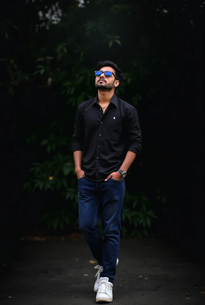 A young pakistani with black shirt navy jeans and white joggers and black sunglasses on eyes looking at sky with natural dark background in backdrop with a subtle black lighting of the rate site posing for professional photo