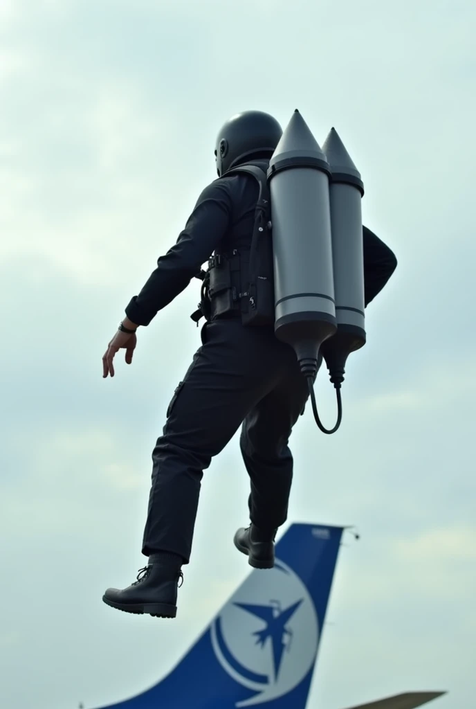 A person equipped with a jetpack is flying above the ground, dressed in a black flight suit and helmet. The background features an airplane tail, with a blue and white design, suggesting an airport setting. The sky is slightly cloudy, emphasizing the altit...