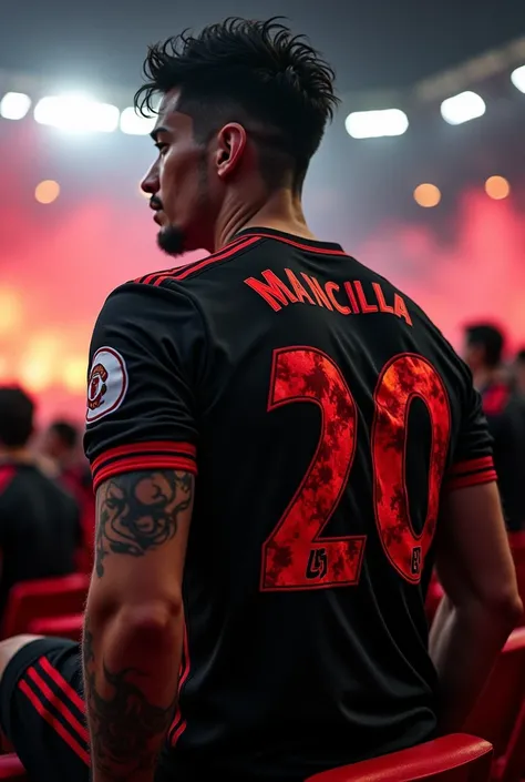  white man,  short wavy black hair ,  has a tattoo on his arm, Eclectic physique , muscular,  wearing a black Manchester United jersey with red details on the shoulders and the texture of fiery flames on the sides and in the jersey number. Sitting in the s...