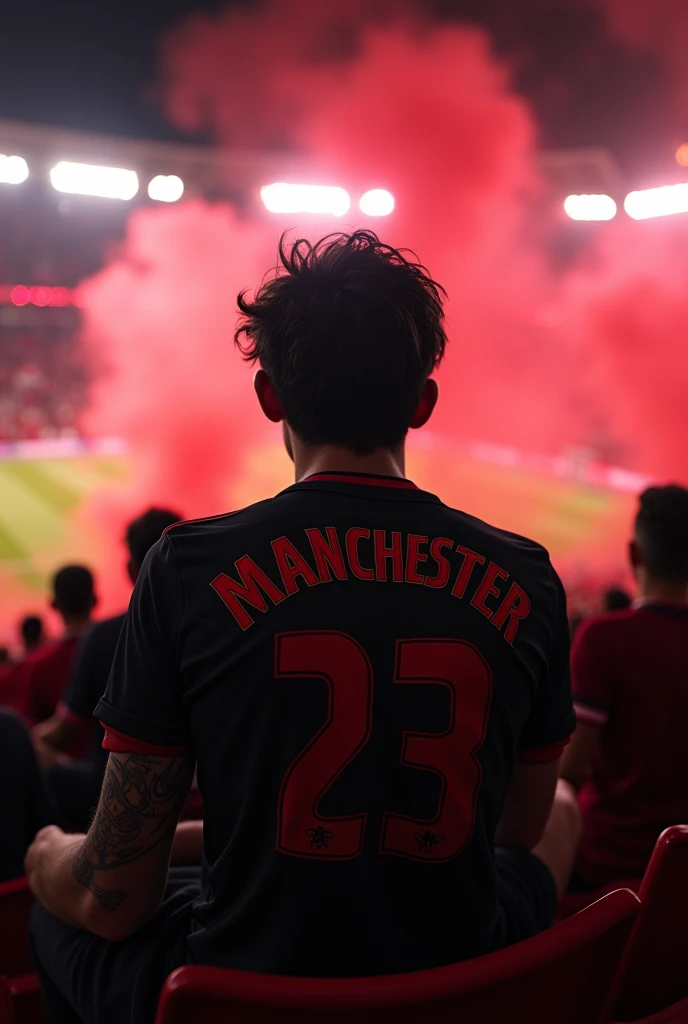 front angle, 23-year-old white male ,  wavy black hair,  has a tattoo on his arm, Eclectic physique ,  wearing black Manchester United jersey. Sitting in the stands of a soccer stadium at night,  with Manchester fans with red smoke 
 
