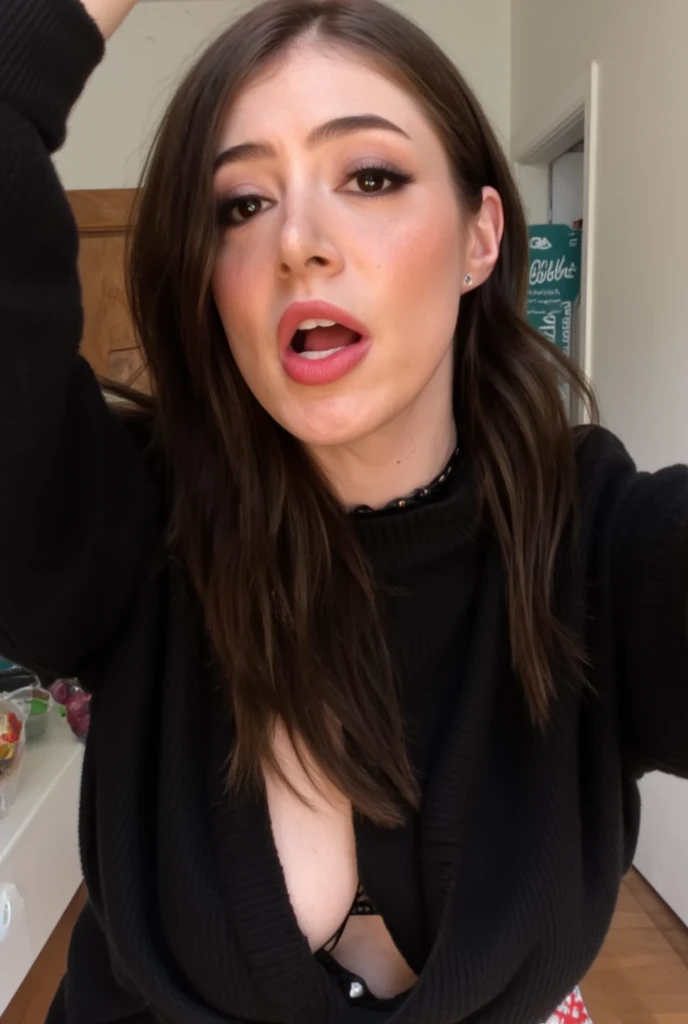 A selfie of chrissy from above, she is wearing a black sweater displaying her cleaving, her right hand is raised up above her head to take the selfie, choker necklace, looking straight at the camera
