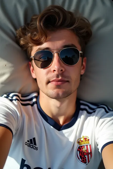 I took a selfie Im lying down Im wearing sunglasses and a Real Murcia Football Shirt Im a 19-year-old man with short wavy messy hair 