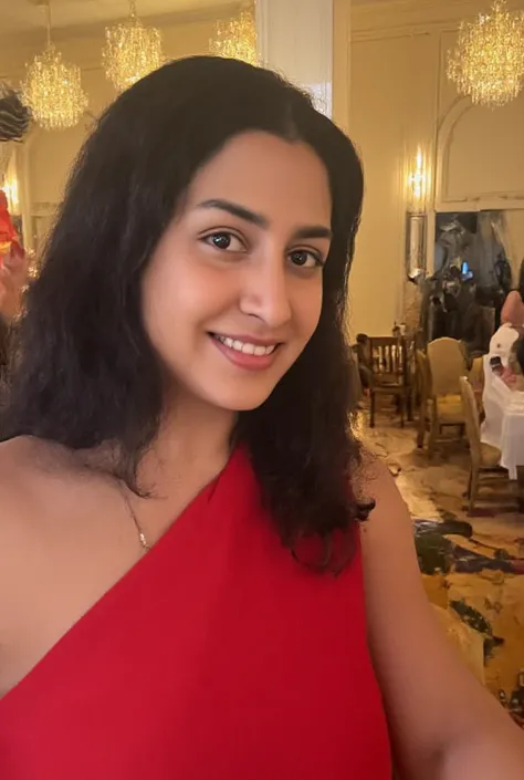 A gorgeous iNDIAN woman in her mid-30s with shoulder-length, silky black hair, styled in loose curls. She has deep brown eyes, smooth olive skin, and a radiant smile. Shes dressed in a sleek red evening gown with a plunging neckline, showcasing her elegant...