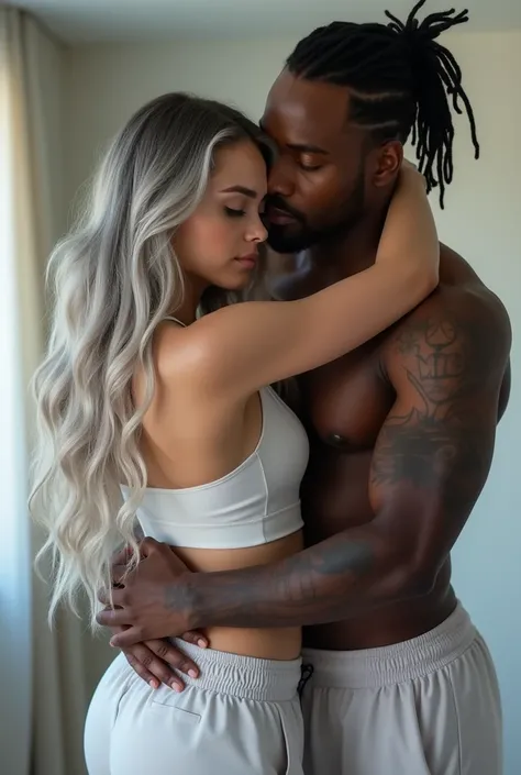 a gorgeous white caucasion woman with silver grey lilac tint ombré Long wavy hair. she is standing looking in the mirror and standing behind her with one arm around the front of her shoulders in an embrace facing the camera is a very tall muscly black afri...