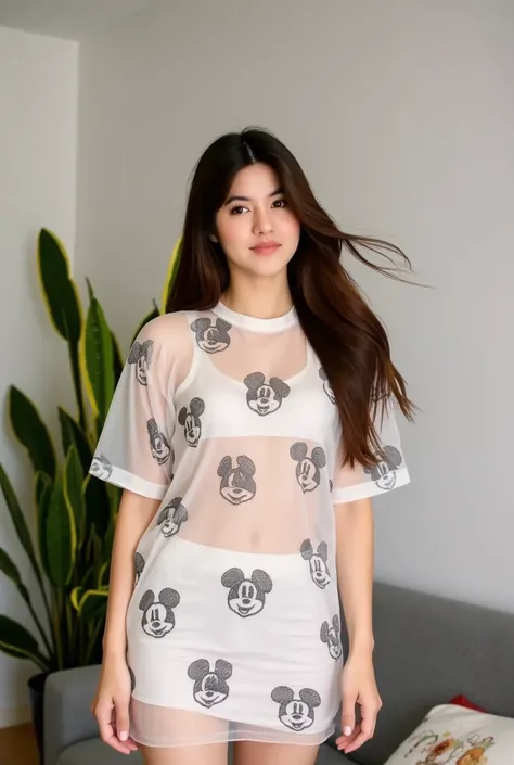 a young woman stands against a living room. She is dressed in a sheer oversize mini dress adorned with a pattern of micky mouse. Her hair is long brown adding a touch of movement to her face. The womans dress is adorned in a batic patern. She stands tall