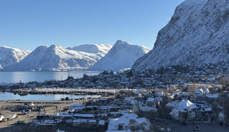 "A small fishing village situated in a sheltered nook of the rugged northern coast. The village houses are built on stilts, extending over the fjord, with nets hanging from balconies and boats docked just below. The waters here have a supernatural glow, re...