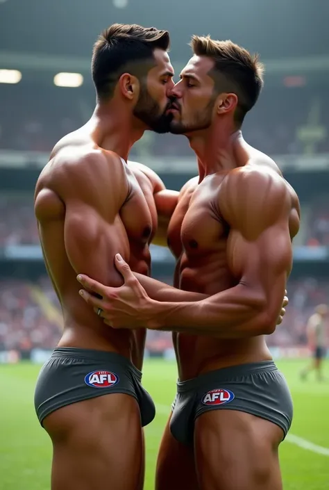 Two toned and muscular men are wearing tight and small grey thong underwear with afl logo and are kissing in a stadium