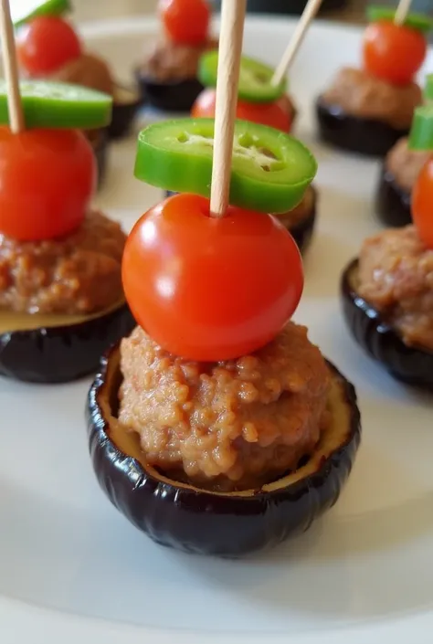 
Place half a cherry tomato slice and a pepper slice on a small meatball, baked in the oven, with a thin eggplant slice wrapped around it from top and bottom. Let a toothpick be inserted into them from the top.