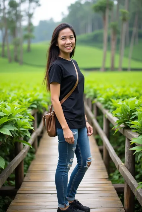 Beautiful Indonesian girl standing on a wooden bridge with a green and lush tea plantation in the background. The woman is wearing a black t-shirt, jeans with some rips, and casual black shoes. She is also carrying a small bag with a long strap across her ...