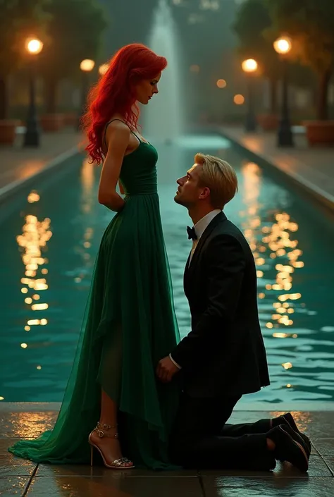 Red-haired woman in an ankle-length emerald green dress and gold heels . a blond man in a black suit kneeling in front of her in a fountain at night 