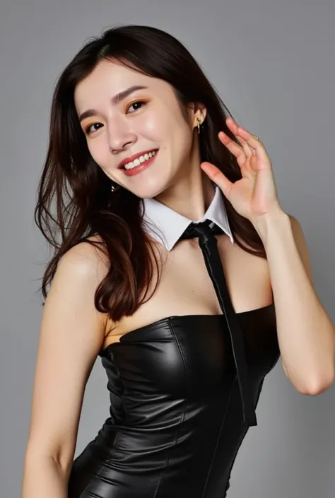 The image is a portrait of a young woman posing in a black strapless leather leotard. She is standing with her body slightly turned to the side, with one hand on her hip and the other resting on her head. The woman has long dark hair that is styled in loos...