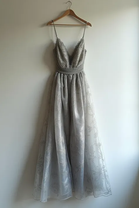 A silver dress with darker gray swirls lay on a wall with a hanger.