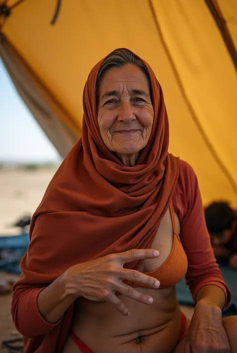  Inside a big close refugee tent ,  The inside of the tent is a mess a 60-year-old Arab woman in a hijab and bikini, Shes smiling but worried , elle est de dos mais tourne donc visage vers moi,  elle fait signe de venir, photo prise de loin, on voit son co...