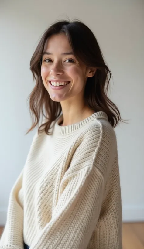 A 35-year-old woman in a soft, oversized sweater, smiling in a minimalist studio setting.