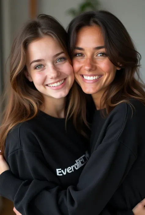 Young white woman with long brown hair and green eyes wearing a black sweatshirt, on the sweatshirt it says "Everbyteclub" and she is hugging a woman with shoulder-length brown hair and brown clear skin, their eyes are black and they are both happy.