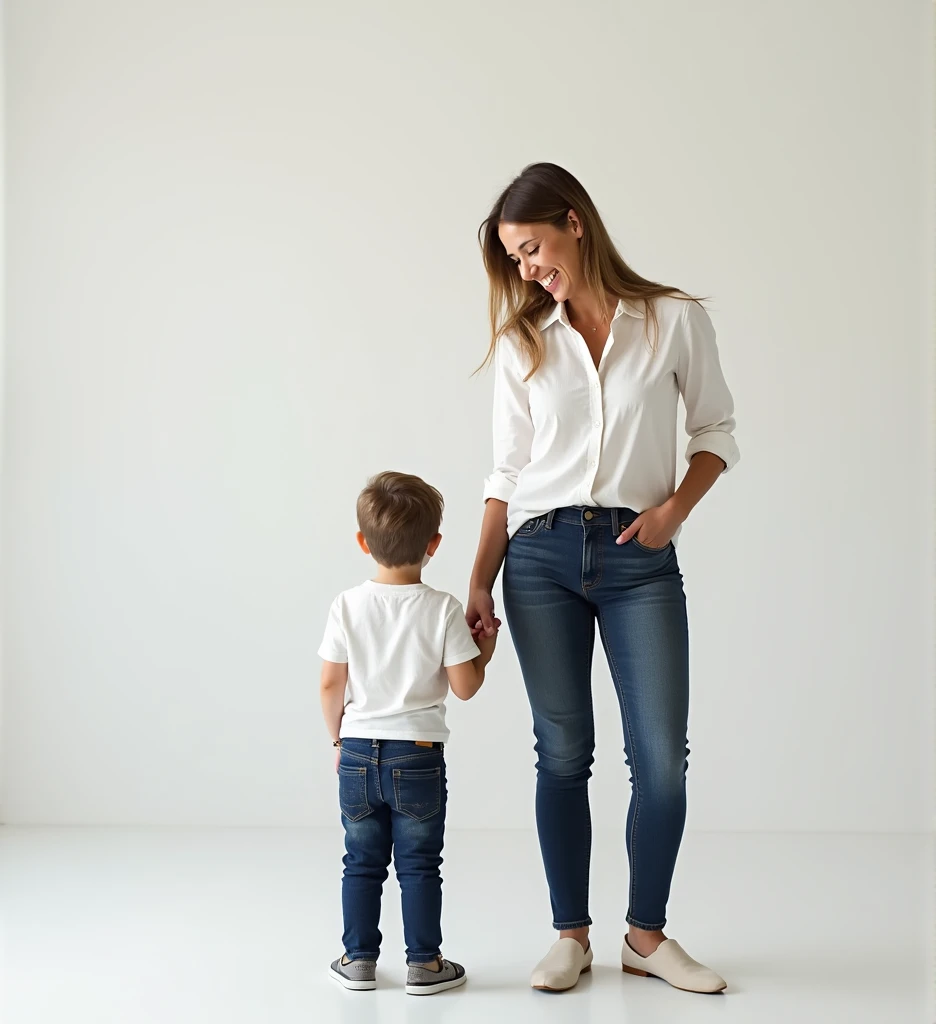 A smiling woman stands next to a 1. baby boy  both facing forward. The woman wears a white shirt and , paired with dark jeans. The boy, holding the womans hand, is dressed in a white shirt and blue pants, with matching shoes. They are set against a plain, ...