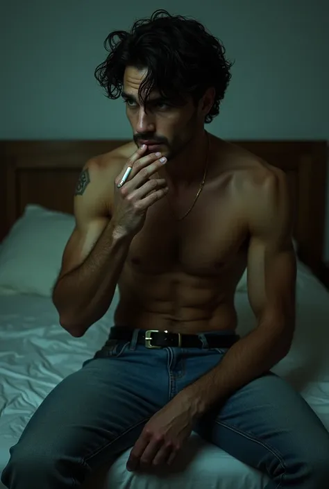 A guy with a sculpted torso, curly black hair,  green eyes , dressed only in blue jeans ,  sits on the edge of the bed smoking a cigarette 