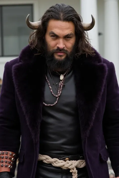 Jason Momoa,long black hair, very long mustaches of the same color and a pronounced goatee also black. He also has long white horns curved on the sides of his head.He wears a braided white rope as a belt and bracelets with sharp spikes. He has a massive da...