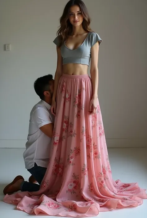 Create an image of a beautiful lady with very large breasts and  in a grey short arm very short crop top and extremely long adorable rose floral pink chiffon skirt. Skirt edges covers the floor and spreads along the floor, she is standing. man is kneeling ...