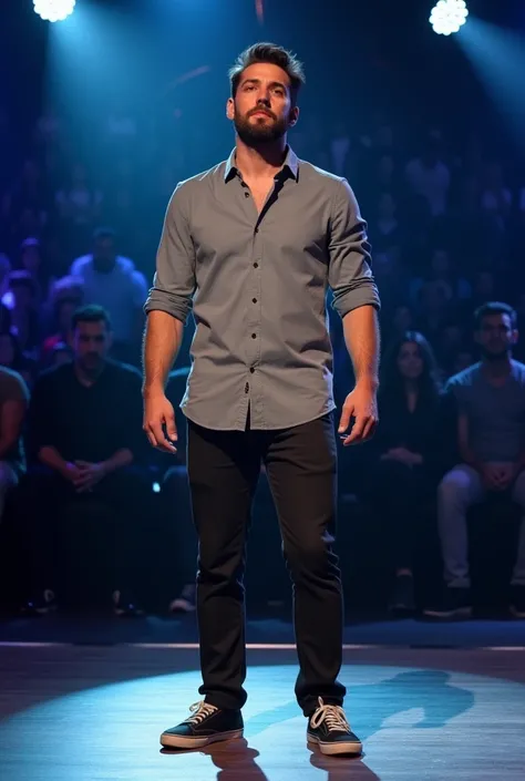 A man standing confidently, fully facing the camera on an American talent show stage. He is looking directly into the camera with a determined and focused expression, ready for his performance. The man is wearing casual clothes: a simple shirt, pants, and ...