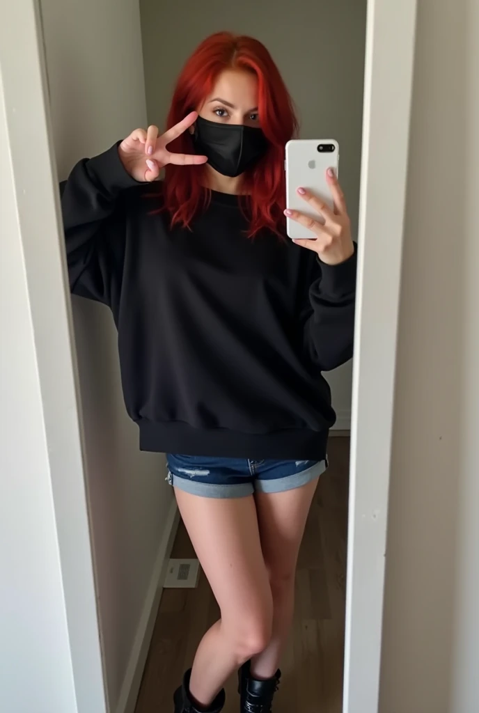   white woman with red hair wearing a black mask and a black sweatshirt showing her belly , She wears dark blue denim shorts and short black boots , she is making a v with her hand while holding her cell phone in the other hand taking a picture in front of...