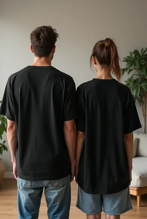 A young father, young mother with her hair tied back in a ponytail, and their  son standing side by side, facing away from the camera, with their backs fully visible. They are all wearing oversized plain black T-shirts that drape loosely and clearly displa...