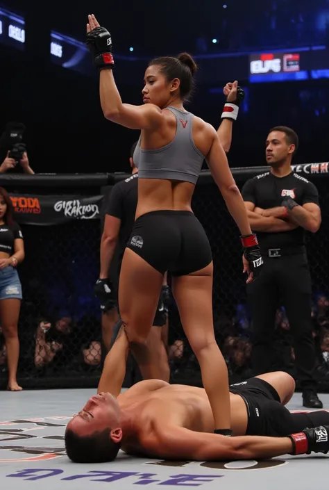 A victorious pankration tournament scene on the mat of a professional grappling competition. An Asian woman with a fit and athletic physique stands confidently, wearing a gray racerback sports bra, black athletic shorts, and MMA gloves. Her stance is stron...