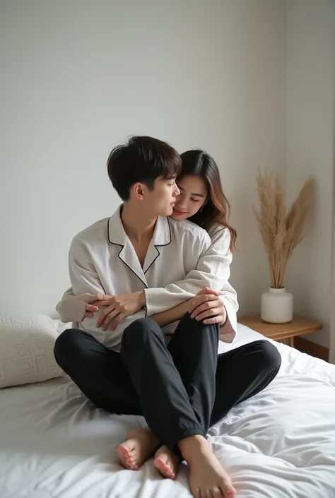 A Korean handsome guy in a pajama shirt sits on a mattress and a Korean hottie wears black pajama pants inside the arms Korean handsome guy hugs a chick from behind a white ash ash minimalist room decor