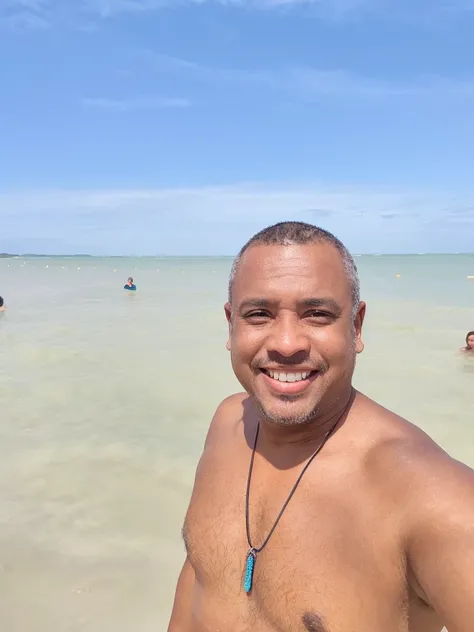 there is a man that is standing in the water with a necklace, O oceano ao fundo, em uma praia tropical, oceano ao fundo, on the ocean water, Homem de 4 0 anos, Homens de 45 anos, no meio do oceano!!!!!, na praia, no mar, O mar ao fundo, vacation photo