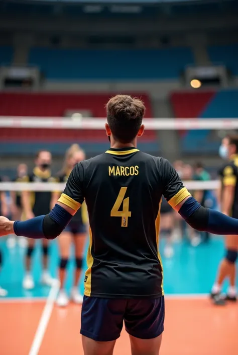 " A volleyball player on his back ,  with white skin ,  wearing a black t-shirt with the number '4' and the name 'Marcos' printed in letters Black.  The shirt has yellow details on the edges of the sleeves .  He wears dark blue knee pads and black elbow pa...