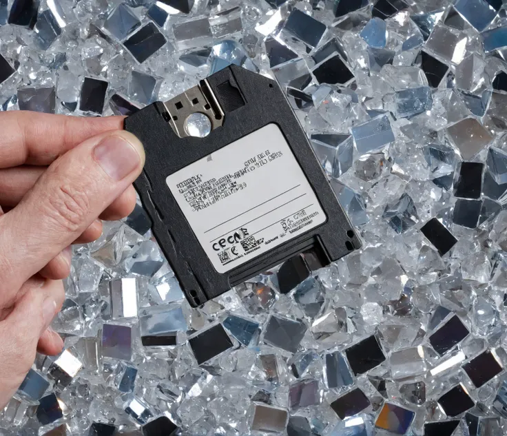 the floppy disk is held by a clawed hand, crystals