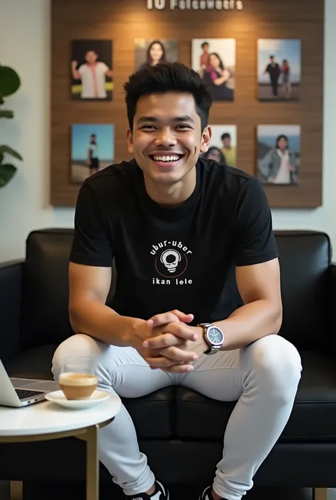 An Indonesian man with a warm smile faces the camera, sitting on a small black sofa in front of a wall that says 10 Followers which is full of colorful photos. Wearing a black t-shirt with the ''Ubur-ubur Ikan Lele'' logo on the front, white tights, and mo...