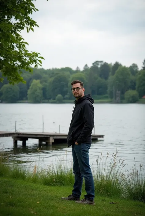 there is a man standing on the grass by the water, a picture by Robert Zünd, instagram, happening, lake in the background, near a jetty, in a park and next to a lake, at the waterside, near a lake, standing next to water, with a park in the background, riv...