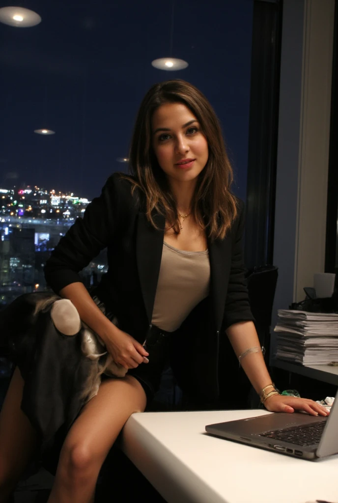  A young woman with dark blonde ,  shiny hair poses confidently and sensually on the Edge of a modern desk in an elegant office .  She wears chic ,  figure-hugging office clothes — a tailored Blazer with a silk top underneath and a tight-fitting pencil ski...