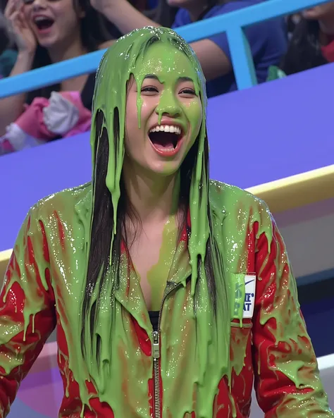 A young Korean woman with long black hair and light skin in a brightly lit game show studio, covered in thick, dripping green water. She wears a red jumpsuit, which is partially visible beneath the slime.  The red jumpsuit is partially unzipped, revealing ...