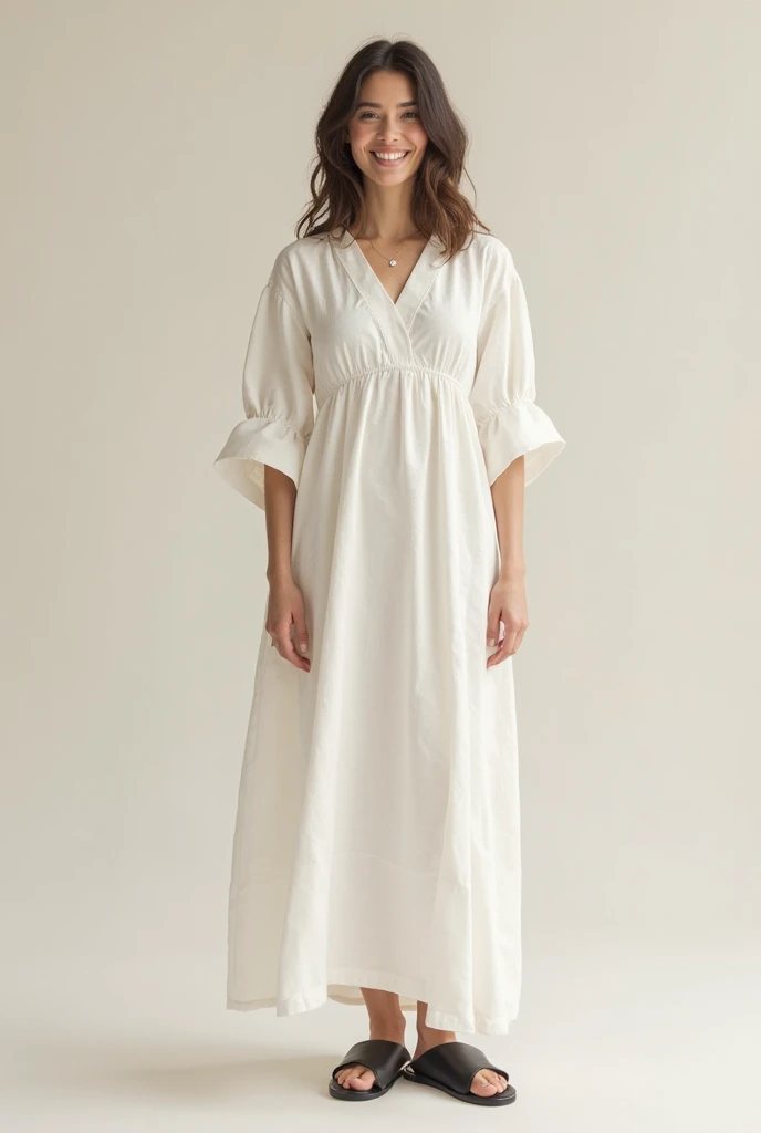 smiling brunette woman wearing a long dress, simple, crease-free, Of white linen, without details, wide sleeves below the shoulders and black sandals without heels
