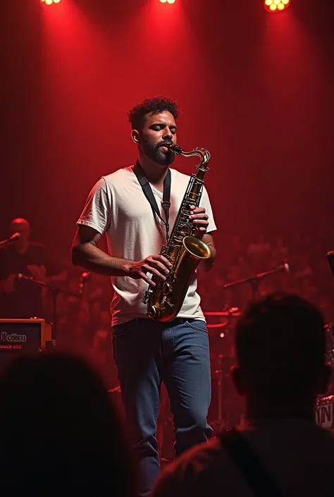 A man in a white T - shirt and blue jeans is playing a saxophone on stage. The warm red light bathes him, and the rich and mellow sound of the saxophone fills the air.