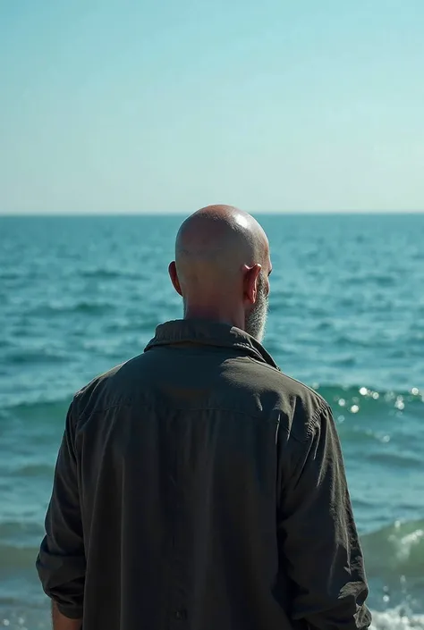 A bald man infront of the sea