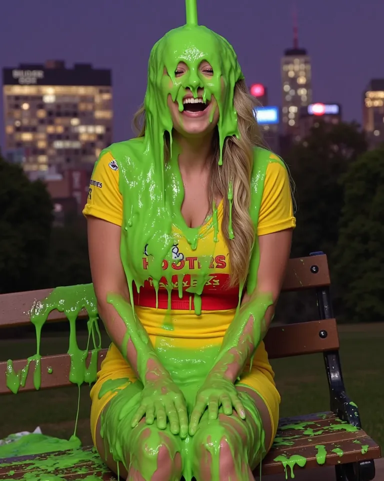 DSLR photograph of young woman with long wavy blonde hair sitting on a park bench at night, covered in thick, dripping green water. New York city skyline in the background. Bokeh. She wears a Hooters waitress uniform, which is partially visible beneath the...