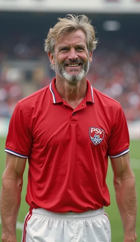 A portrait of a veteran Dutch footballer aged 42-45, wearing a classic red PSV Eindhoven jersey (without logos or ads) and white shorts. His hair is short, with a few visible gray strands, he wears a very well arranged beard, and his face has a smiling, fo...