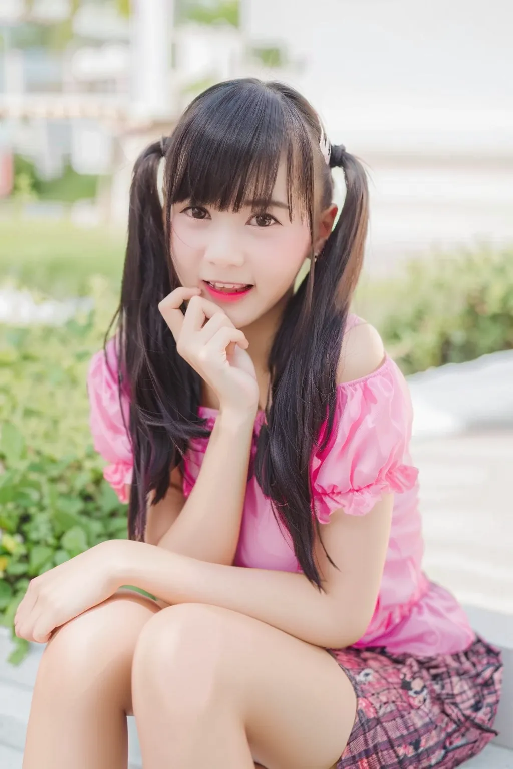 close-up of a woman sitting on the steps with her hands on her chin,  Thai Girl Anime ,  pink twintail hair and cyan eyes, Cute Kawaii girl, Twintail, Twintail hairstyle,  , a real-life anime girl , Double braided hairstyles, Black hair ,  cute cartoon gir...