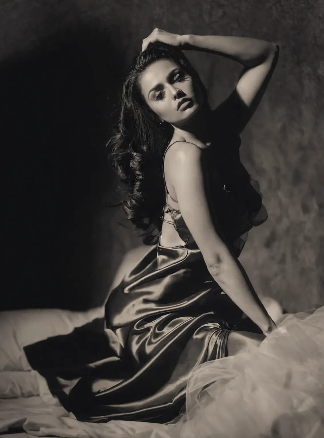 arafed woman in a dress sitting on a bed with her hands on her head, glamorous pose, 