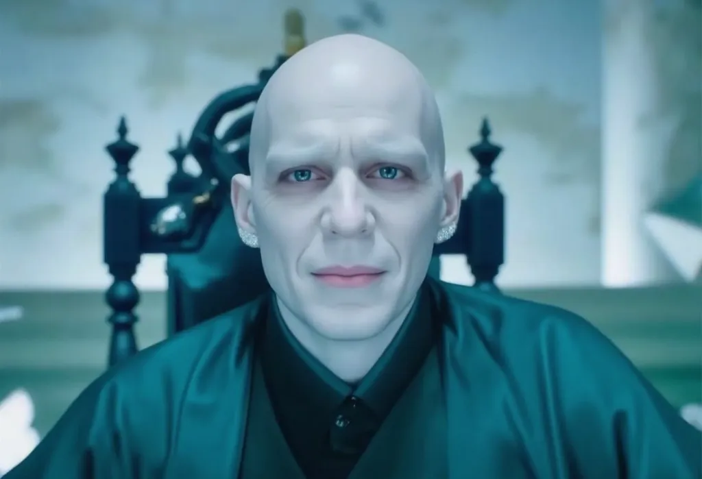 "A sinister and dominant gangsta-style portrait of Lord Voldemort, captured with a high-contrast, eerie lighting effect. He wears a dark, silk-trimmed robe with modern, high-fashion elements, dripping in wealth and power. A massive, custom gold snake chain...