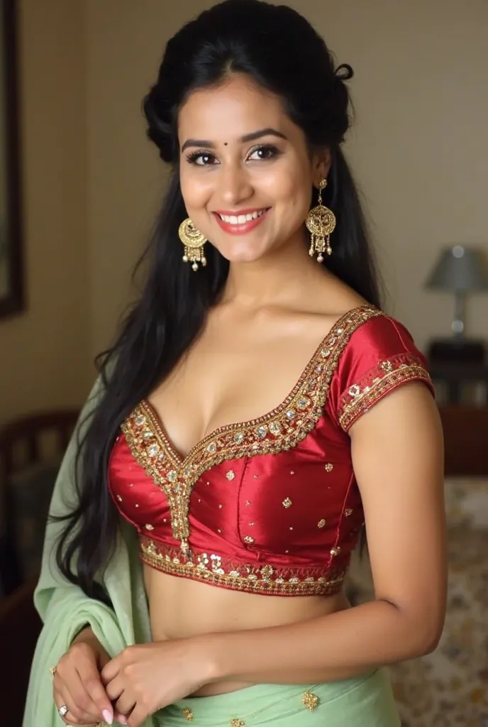 "A young woman with long dark hair tied up in a stylish half-updo, wearing large decorative earrings. She is dressed in a red and gold heavily embroidered blouse with a sweetheart neckline, paired with a light green saree with gold detailing. She poses con...