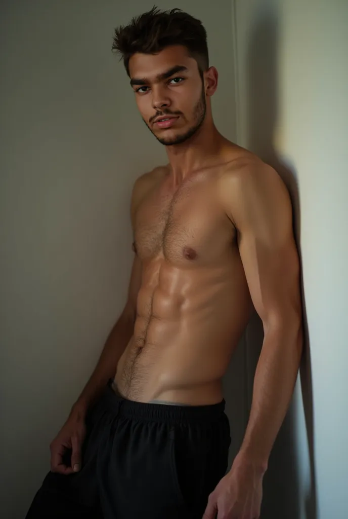 Young shirtless man Leaning Against a Wall wearing a black trouser with a hue bulge on the crotch