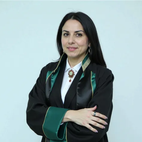 An Azerbaijani female lawyer in a courtroom, wearing a dark suit with a white shirt underneath. She is in the process of putting on her traditional Azerbaijani lawyer's robe—her arms are already through the sleeves, and she is about to pull it over her sho...