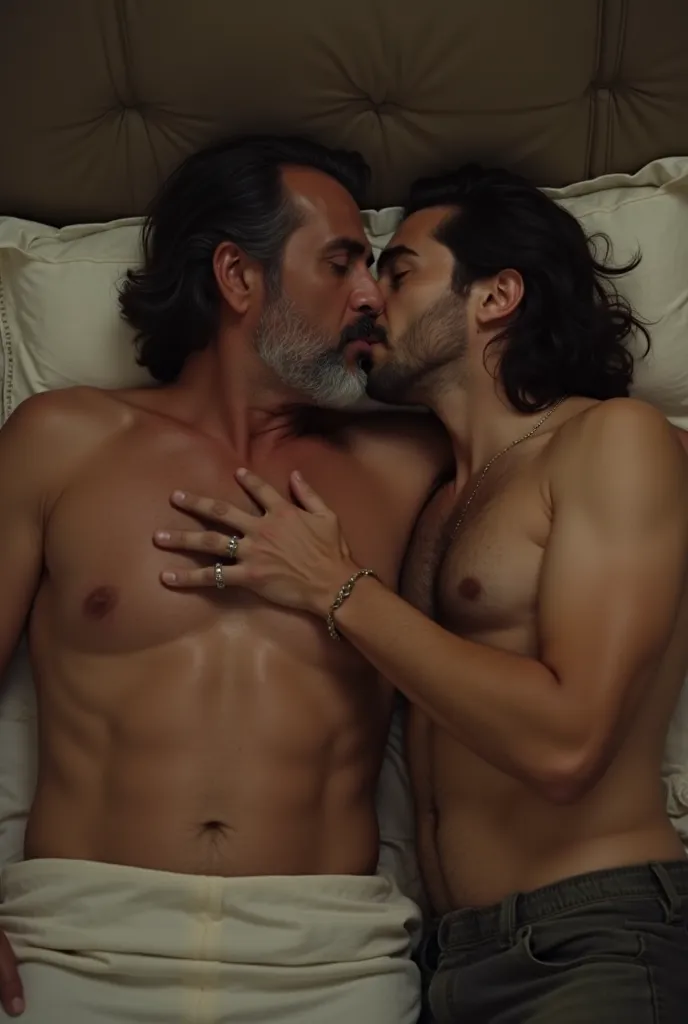 Handsome Latino man with long dark hair and gray beard, about 50 years old, Tall and corpulent, kissing and hugging a young white man with short, burly brown hair,  a few centimeters shorter ,  at night; both are lying in a hotel completely naked 