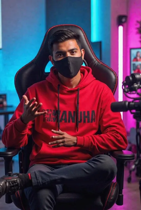 An Indian man sitting confidently on a modern gaming chair in his You Tube studio. He is wearing a bright red hoodie with " PM MANJHA " boldly printed on it. His face is clearly visible and expressive despite wearing a sleek black coviD-19 mask. The man is...