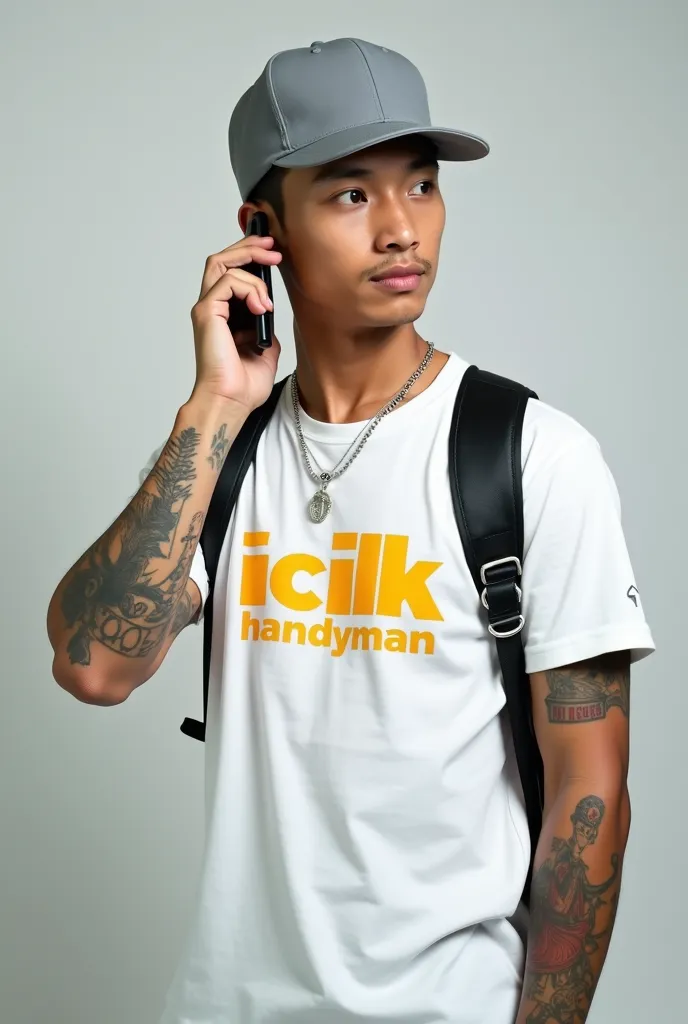 "Make a picture of a young asian man wearing a grey baseball cap . The man was wearing white with yellow and orange text that read 'iclik handyman.' He has a black strap with a transverse silver buckle on his chest. His left arm has several tattoos, includ...